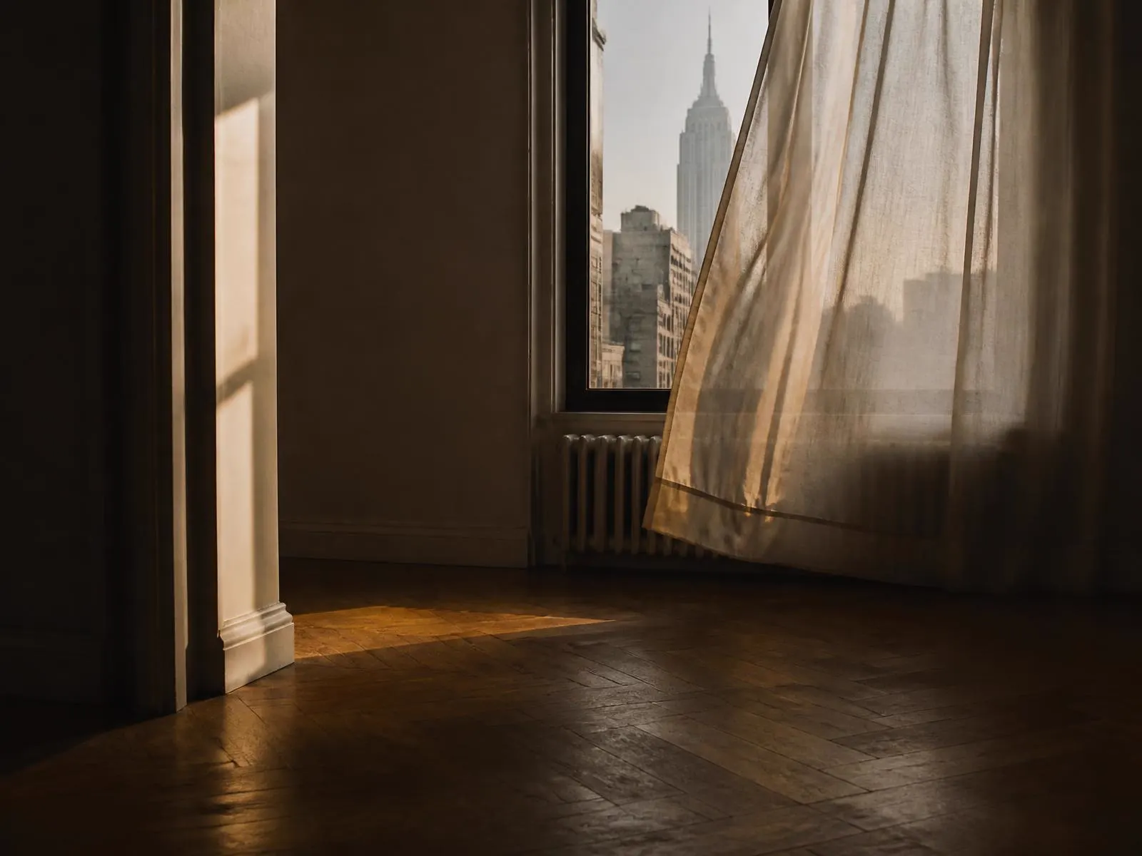 A still, softly lit interior with daylight falling across a plain wall